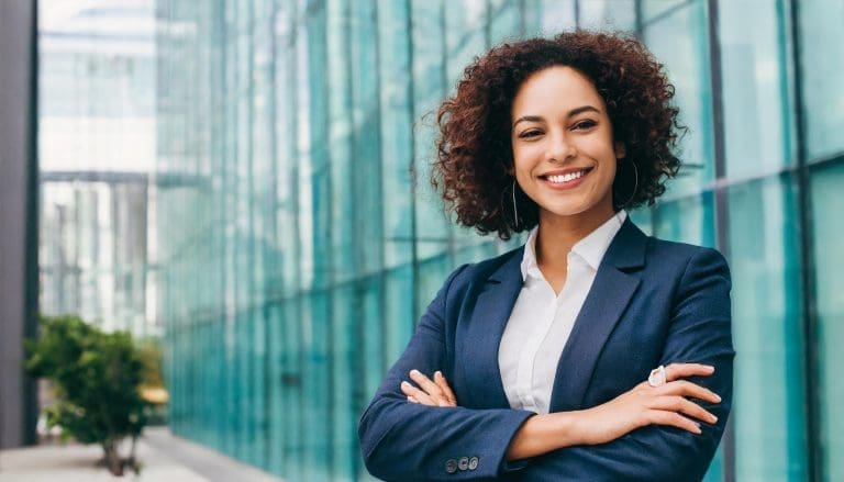 A woman standing with her arms crossed smiling because she knows the secret to successful networking habits.